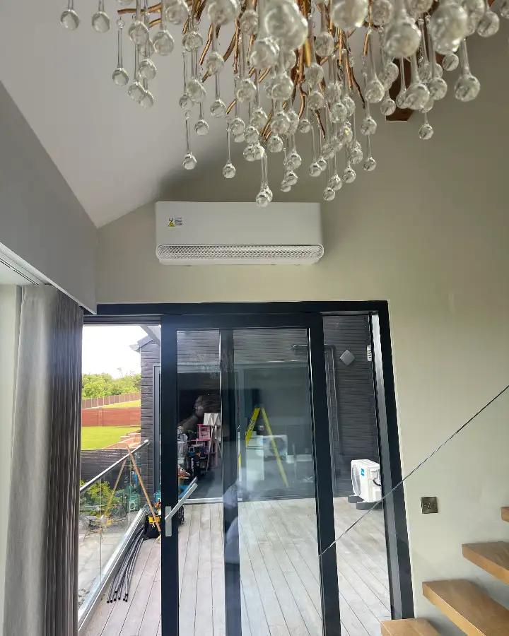 Air conditioning unit installed in a bright, high-ceilinged living space with bi-fold doors
