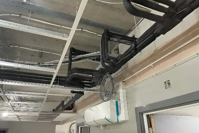 Air conditioning installation in progress with insulated refrigerant pipework run through a ceiling void