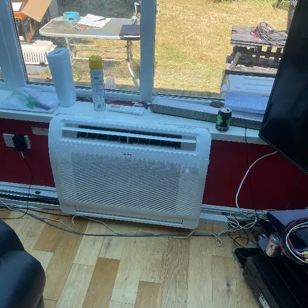 Floor-standing air conditioning unit installed beneath a garden-facing window