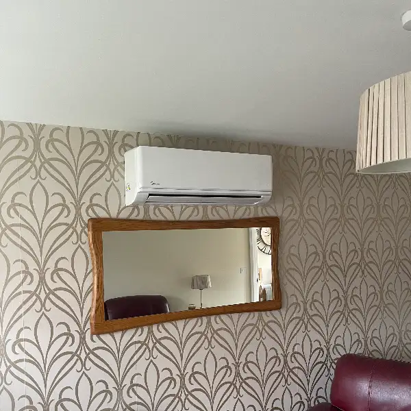 Air conditioning unit installed above a mirror in a lounge with patterned wallpaper