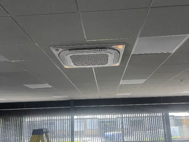 Ceiling cassette air conditioning unit installed in an open-plan office with a suspended ceiling