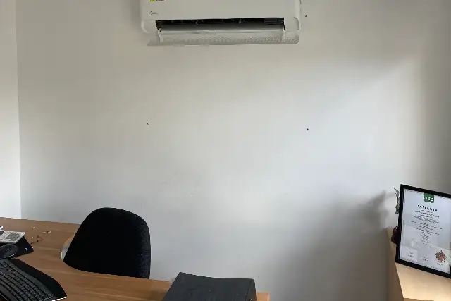 Office air conditioning unit installed above a desk in a small office