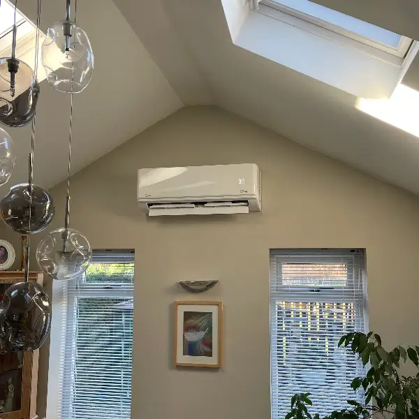 Wall-mounted air conditioning unit in a vaulted living room with a roof window